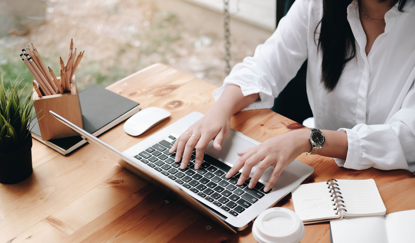 A woman at a desk typing on a laptop.