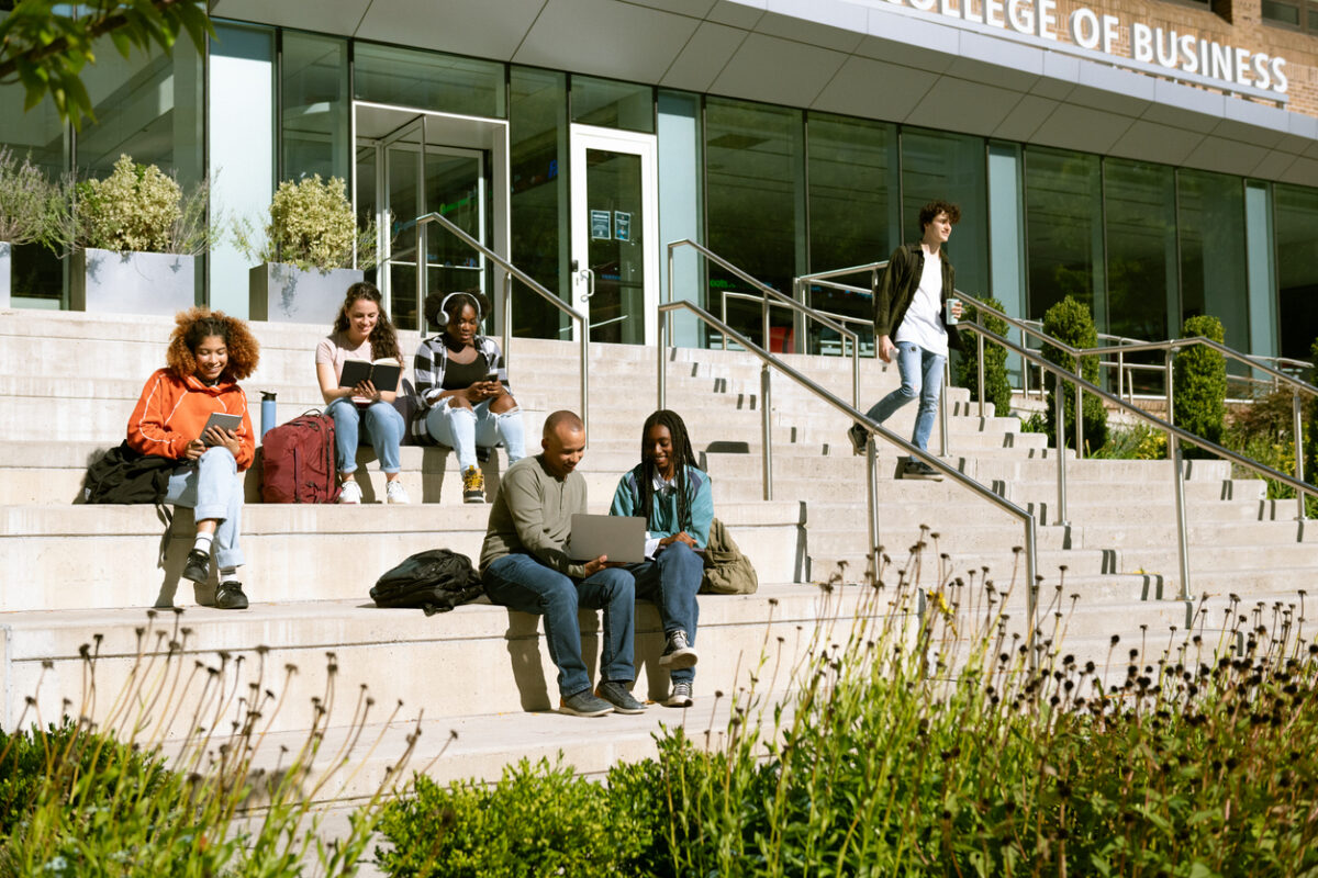 A group of university students sat on the steps of the college building on campus.