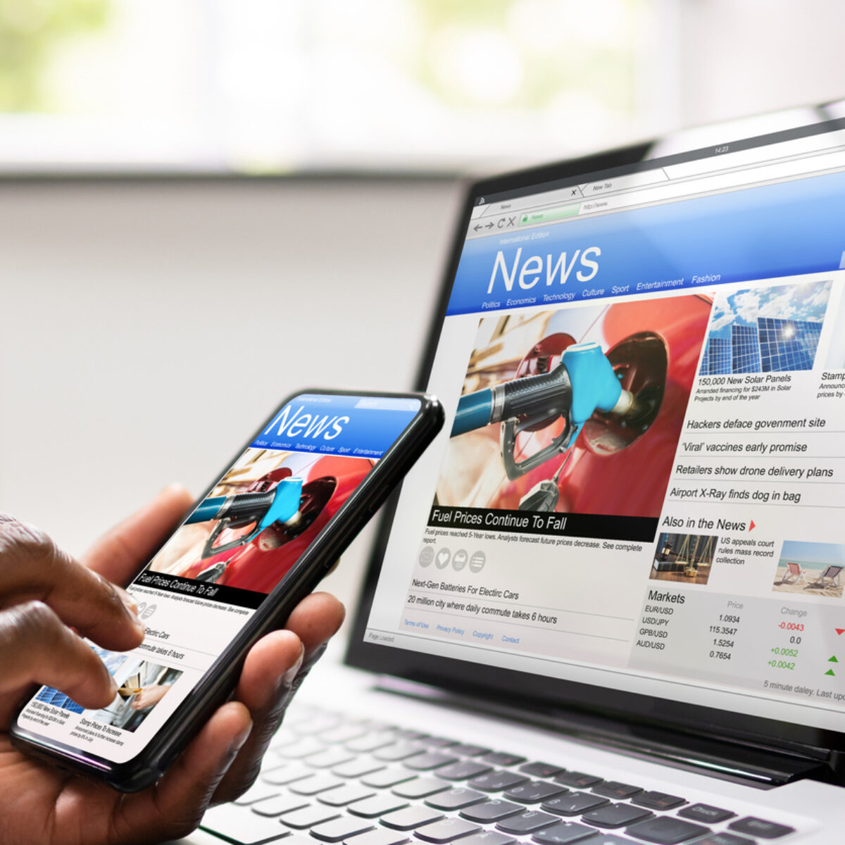 A laptop and mobile phone with a news website open on each screen