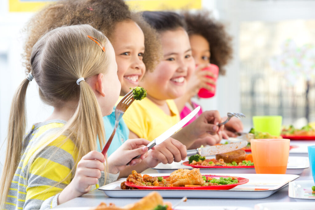 School children sat at a table in the canteen eating their lunch