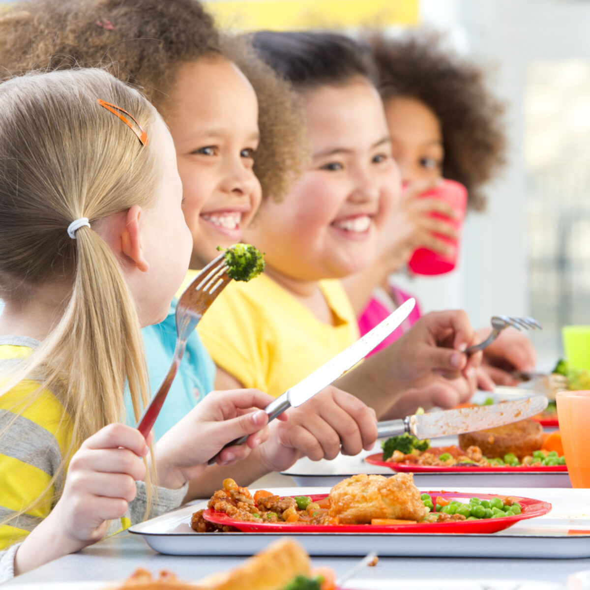 School children sat at a table in the canteen eating their lunch