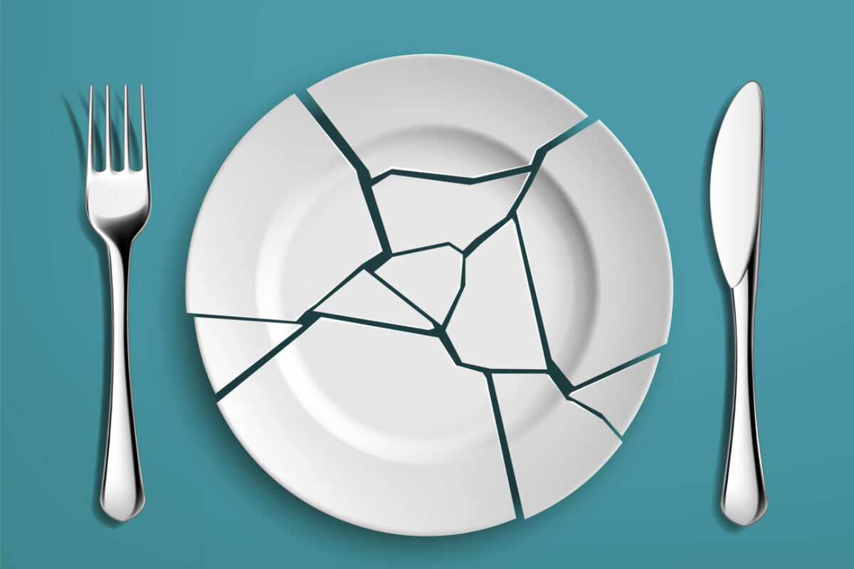 White broken plate with fork and knife on a blue background