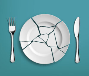 White broken plate with fork and knife on a blue background