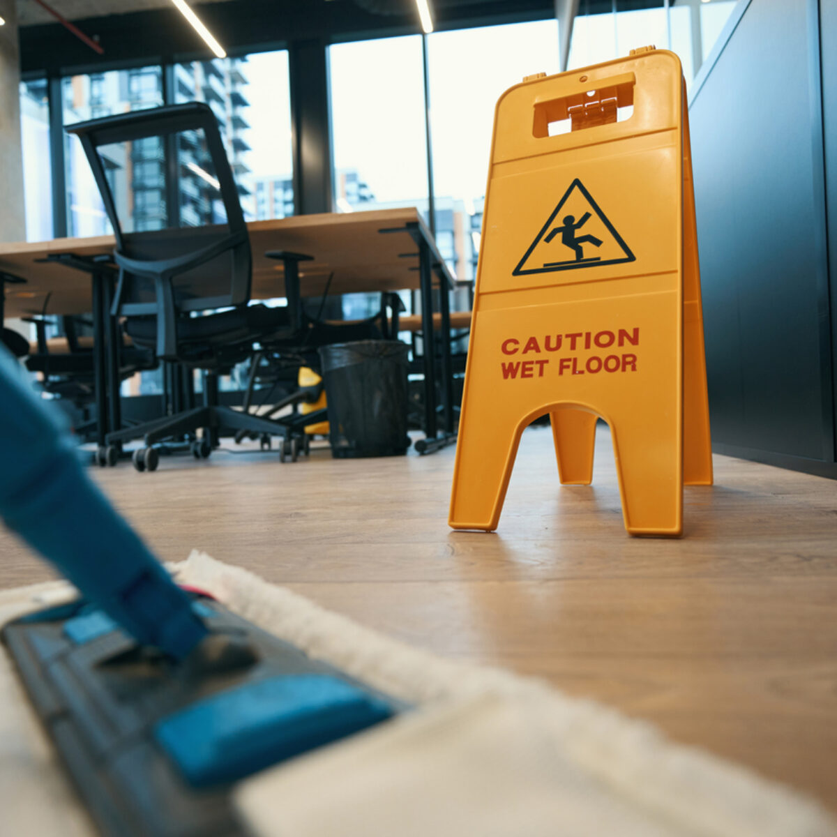 Wet floor cleaners sign in yellow on a wooden floor in an office