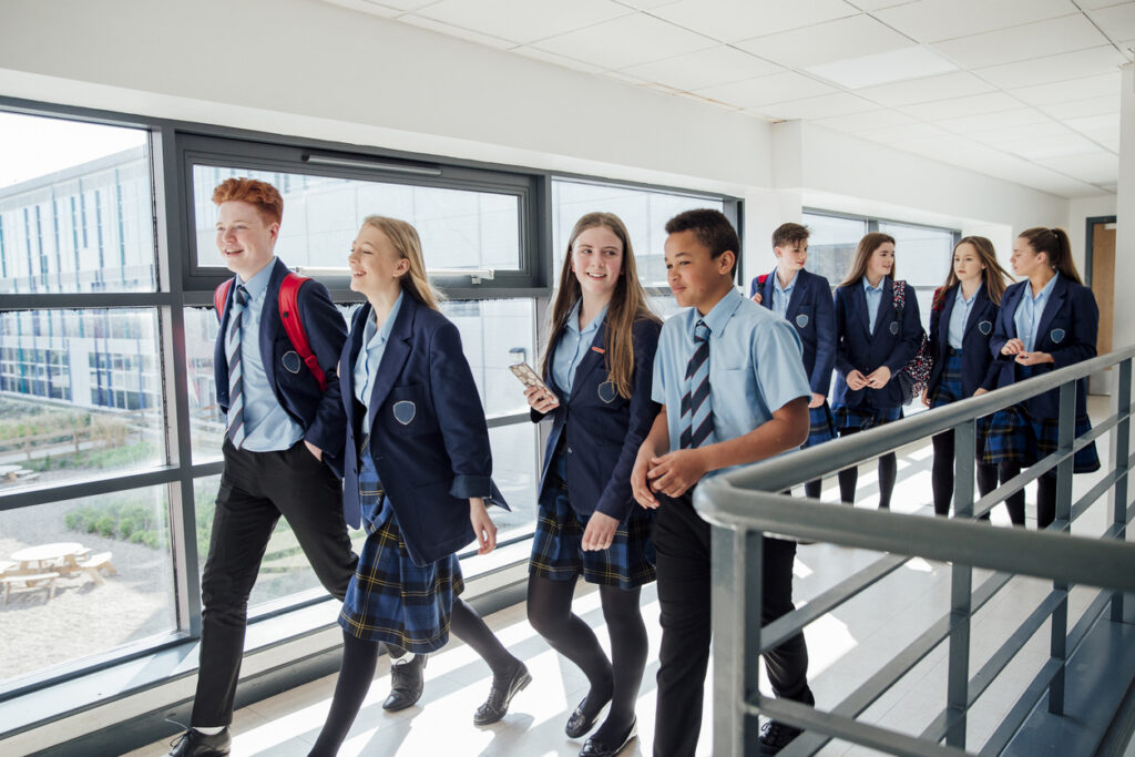High school students in navy uniforms walking in a corridor at a school