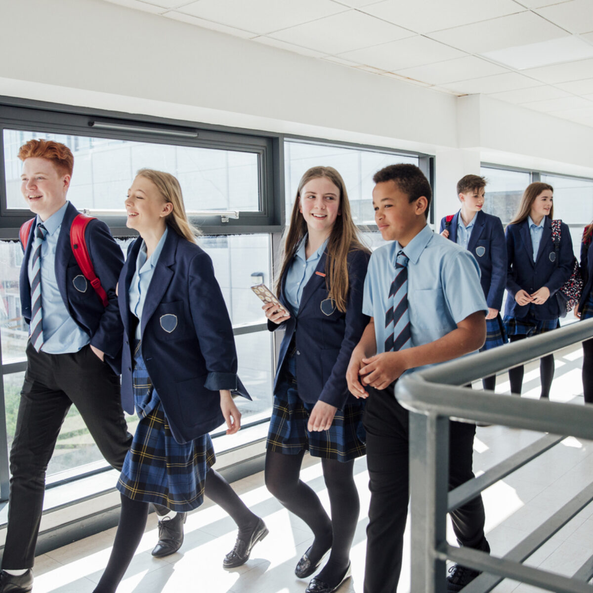 High school students in navy uniforms walking in a corridor at a school