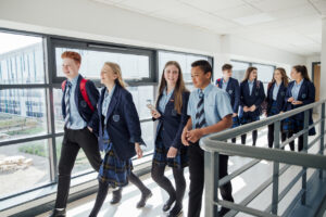 High school students in navy uniforms walking in a corridor at a school